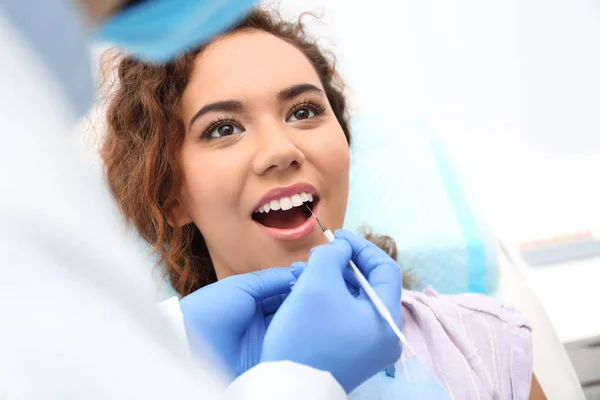 Dentista examinando dentes de mulher afro-americana com sonda no hospital — Fotografia de Stock