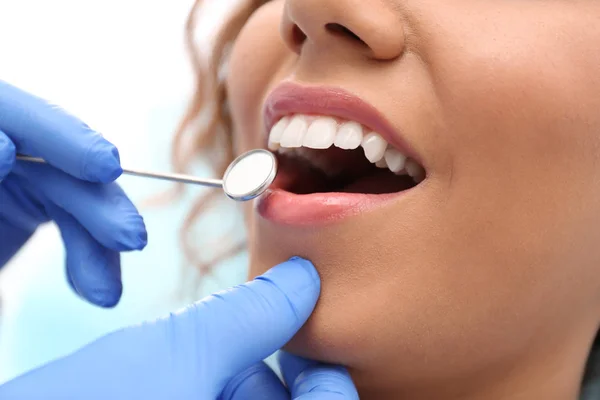 Zahnarzt untersucht Zähne einer afrikanisch-amerikanischen Frau mit Spiegel, Nahaufnahme — Stockfoto