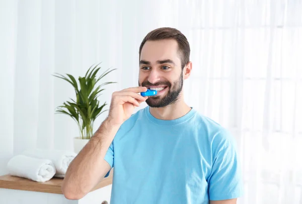 Ung man använder tandblekning enhet hemma — Stockfoto