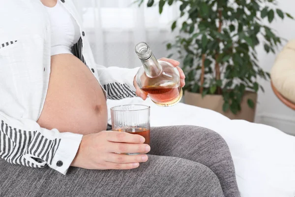 Pregnant woman pouring whiskey into glass at home. Alcohol addiction — Stock Photo, Image