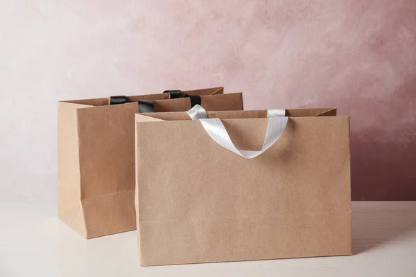 Papírové nákupní tašky na stole barvu pozadí. Makety pro design — Stock fotografie