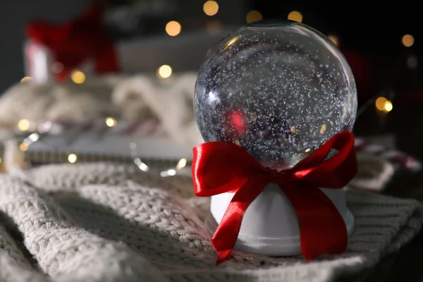 Vánoční sněhová koule s pletením oblečení na rozmazaném pozadí. Mezera pro text — Stock fotografie