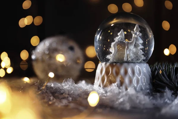 Weihnachtsglaskugel mit Kunstschnee auf Tisch vor verschwommenem Hintergrund. Raum für Text — Stockfoto
