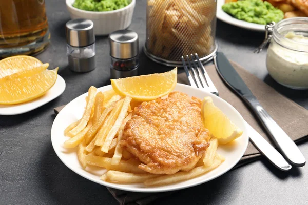Teller mit traditionellem britischem Fisch und Kartoffelchips auf grauem Tisch — Stockfoto