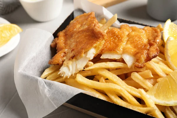 Container med brittiska traditionella fisk och potatis chips på bordet, närbild — Stockfoto