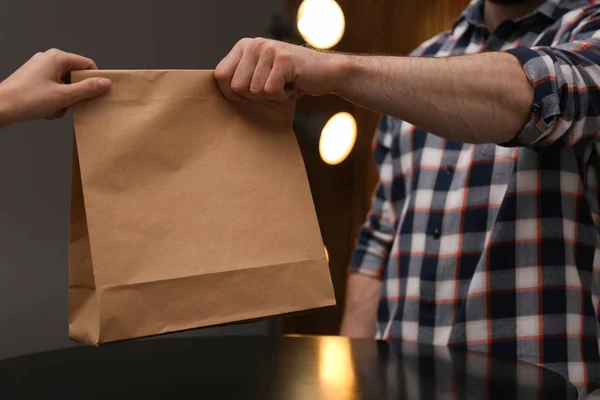 Hombre dando bolsa de papel con el fin de cliente en la cafetería, primer plano. Prepárate para el diseño —  Fotos de Stock