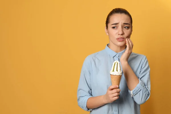 Emotionale junge Frau mit empfindlichen Zähnen und Eis auf farbigem Hintergrund. Raum für Text — Stockfoto