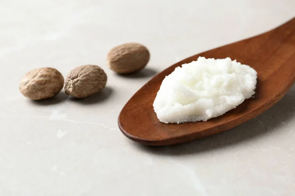 Shea butter in wooden spoon and nuts on table. Space for text — Stock Photo, Image