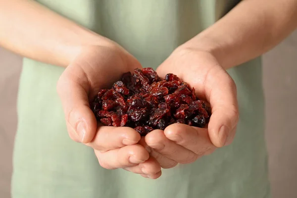 Tartó női maroknyi ízletes vörös áfonya a színes háttér, közelkép. Szárított gyümölcsök, egészséges snack — Stock Fotó