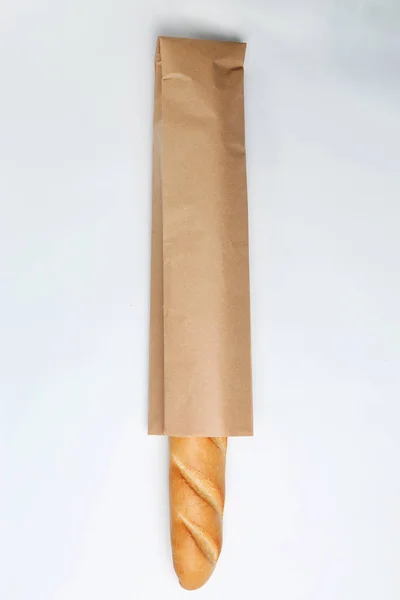 Saco de papel com baguete sobre fundo branco, vista superior. Espaço para design — Fotografia de Stock