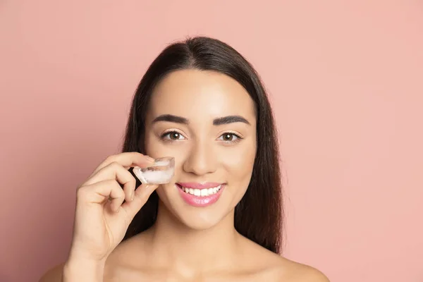 Mujer joven con cubo de hielo sobre fondo de color. Cuidado de la piel — Foto de Stock