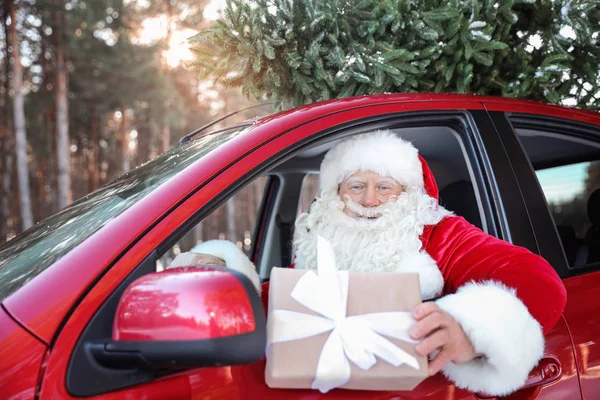 Authentic Santa Claus in car with gift box, view from outside — Stock Photo, Image