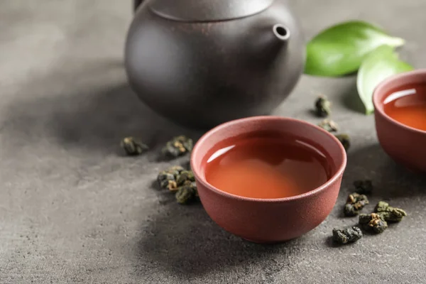 Složení s uvařenou Tie Guan Yin Oolong čaj na šedé tabulky. Prostor pro text — Stock fotografie