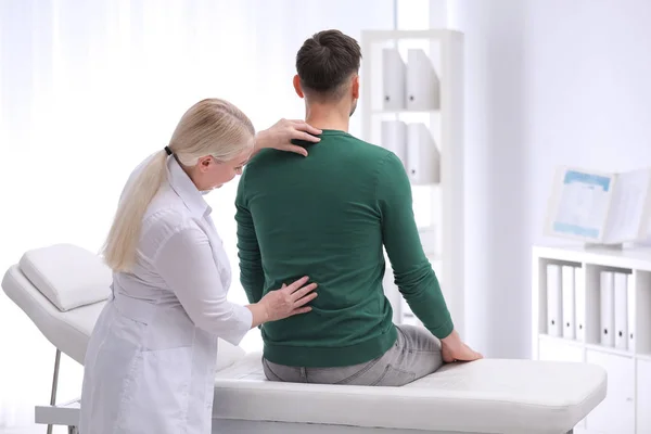 Chiropraticien examinant un patient souffrant de maux de dos en clinique — Photo