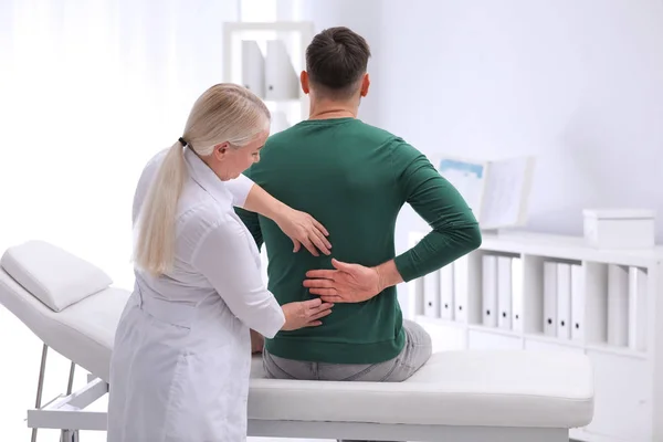 Quiropráctico examinando paciente con dolor de espalda en clínica —  Fotos de Stock