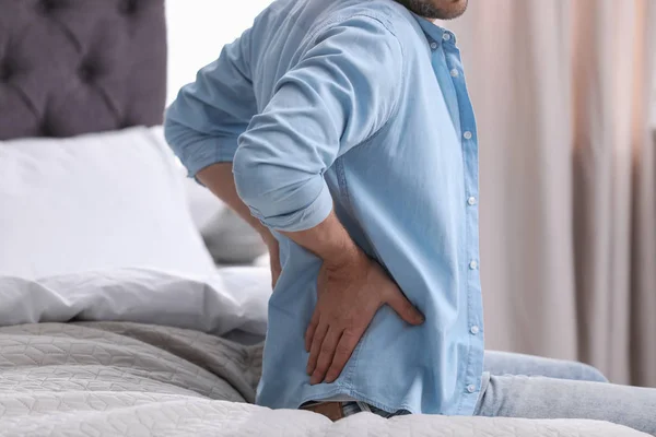 Young man suffering from back pain at home, closeup — Stock Photo, Image