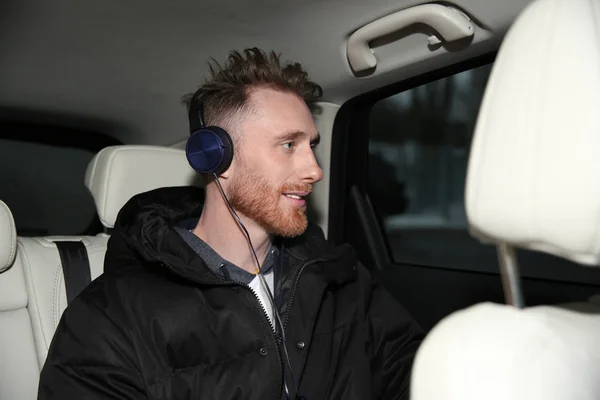 Jeune homme écoutant de la musique avec des écouteurs en voiture — Photo