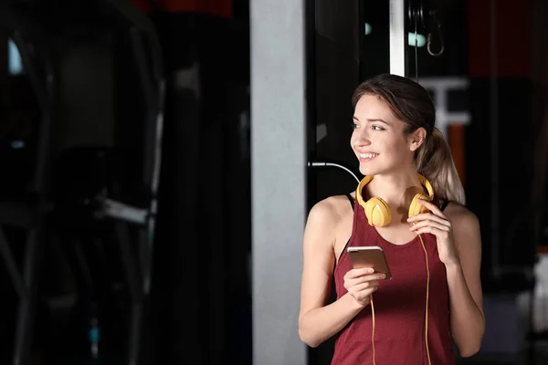 헤드폰 및 모바일 장치 체육관에서 젊은 여자 — 스톡 사진