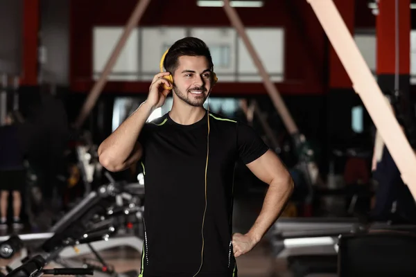 Joven escuchando música con auriculares en el gimnasio — Foto de Stock