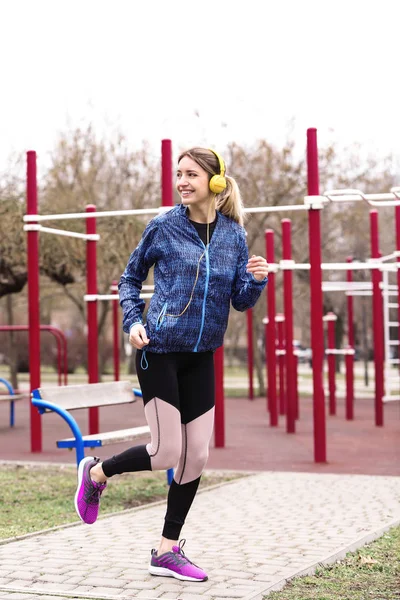 Jeune femme avec écouteurs écouter de la musique et de l'exercice sur le terrain de sport — Photo