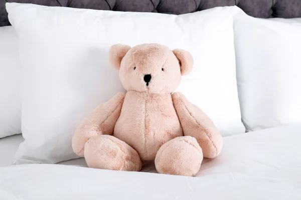 Niedlicher Teddybär sitzt drinnen im Bett — Stockfoto