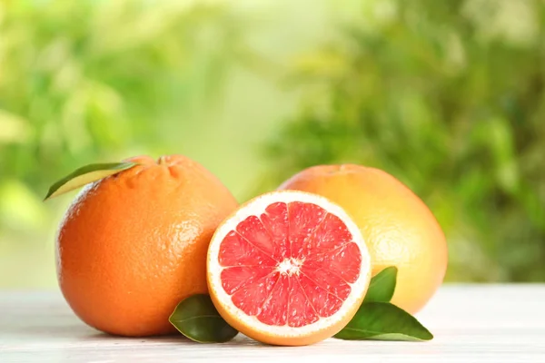 Yummy grapefruits on wooden table against blurred background — Stock Photo, Image