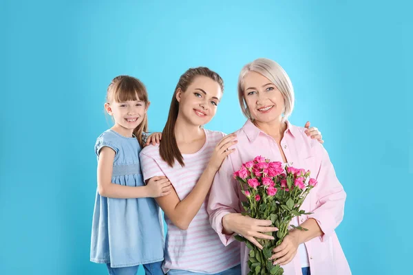 Vacker mogen dam, dotter och barnbarn med blommor på färgbakgrund. Glada kvinnodagen — Stockfoto