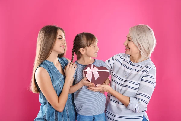 Hermosa señora madura, hija y nieto con caja de regalo sobre fondo de color. Feliz Día de la Mujer — Foto de Stock