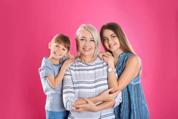 Schöne reife Frau mit Tochter und Enkelkind auf farbigem Hintergrund — Stockfoto