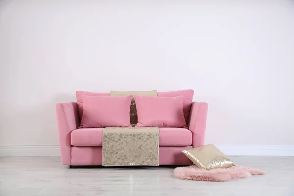 Стильный розовый диван против белой стены в современном интерьере гостиной. Пространство для текста — стоковое фото