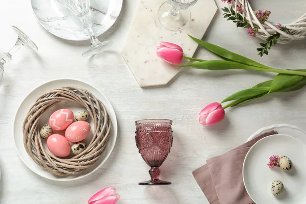 Feestelijke instelling van de tabel van de Pasen met beschilderde eieren op houten achtergrond, bovenaanzicht — Stockfoto