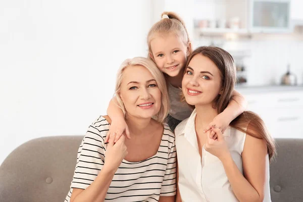 Portrait of young woman, her mature mother and daughter on sofa in living room — Stock Photo, Image