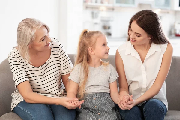 Portrait of young woman, her mature mother and daughter on sofa in living room — Stock Photo, Image