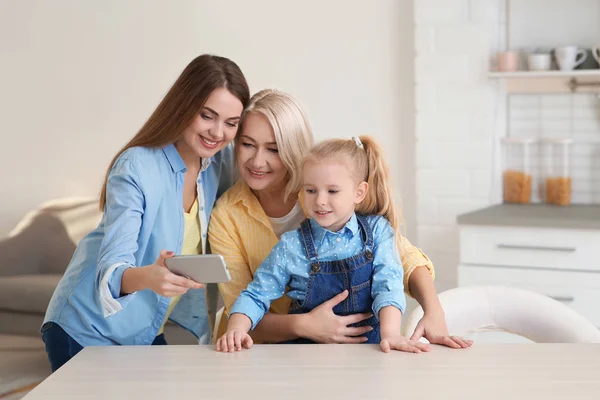 Portrait of young woman, her mother and daughter with smartphone at table indoors — Stock Photo, Image