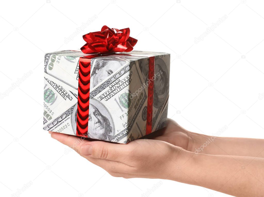Woman holding gift box wrapped in decorative paper with dollar pattern on white background, closeup