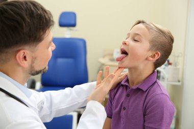 Male otolaryngologist examining little child in hospital clipart