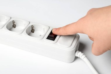 Kadın beyaz zemin üzerine, closeup uzatma kablosu, güç düğmesine basmak. Elektrik teknisyen ekipmanları