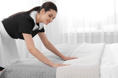 Genç hizmetçi otel odasında yatak yapma. Metin için yer