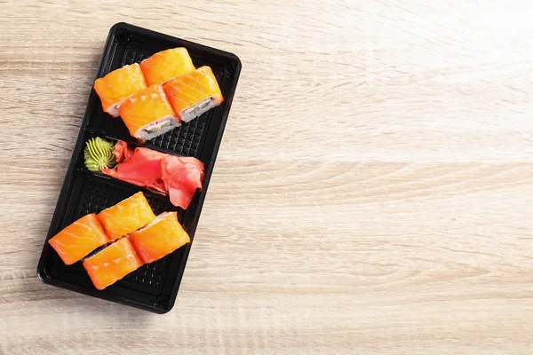 Chutné sushi rolls v poli na dřevěný stůl, pohled shora s prostorem pro text. Rozvoz jídel — Stock fotografie