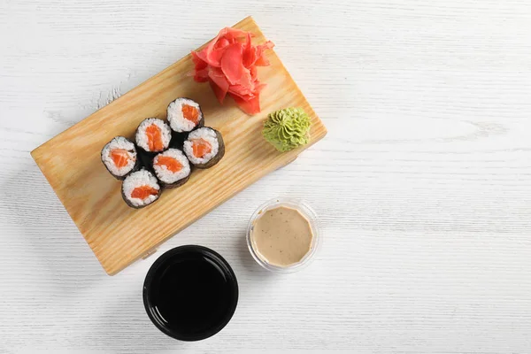 Flat lay composition with sushi rolls and space for text on white wooden table. Food delivery