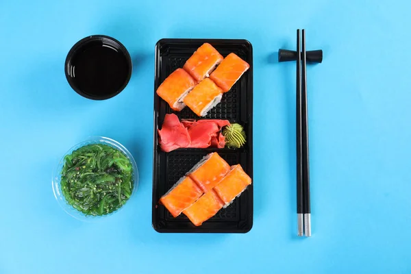 Flat lay composition with sushi rolls on color background. Food delivery