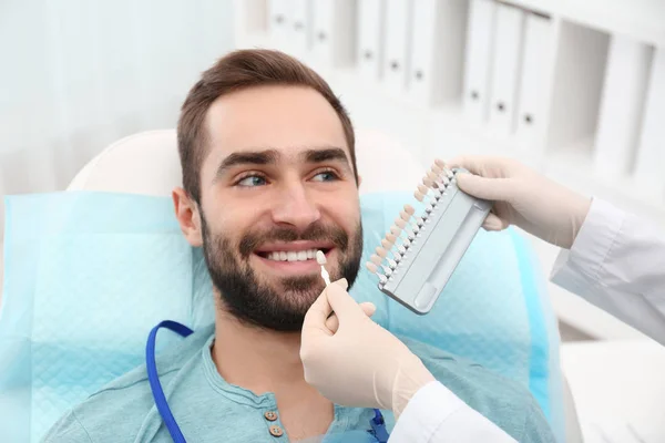 Zahnarzt passt Zahnfarbe des jungen Mannes mit Palette im Büro an — Stockfoto