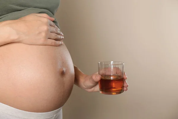 Femme enceinte avec un verre de whisky sur fond de couleur. Addiction à l'alcool — Photo