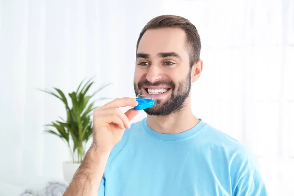 Junger Mann benutzt Zahnaufhellungsgerät zu Hause — Stockfoto