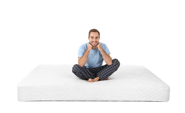 Jeune homme assis sur un matelas sur fond blanc — Photo