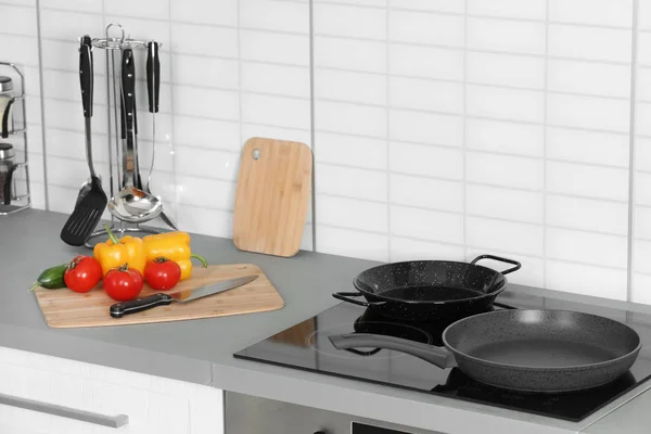 Frigideiras limpas e prancha com legumes frescos na cozinha — Fotografia de Stock