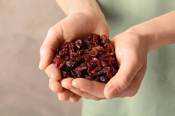 Tartó női maroknyi ízletes vörös áfonya a színes háttér, közelkép. Szárított gyümölcsök, egészséges snack — Stock Fotó