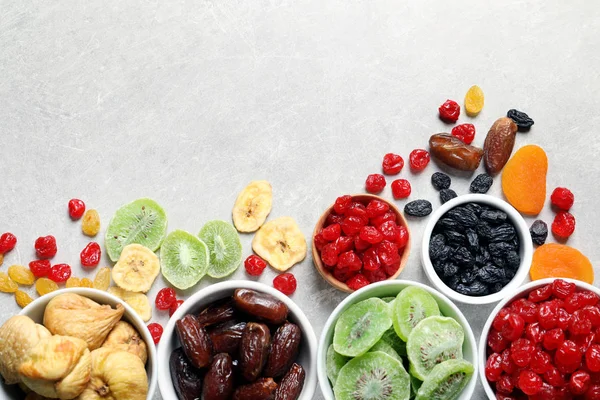 Tigelas de frutas secas diferentes em fundo cinza, vista superior com espaço para texto. Alimentos saudáveis — Fotografia de Stock