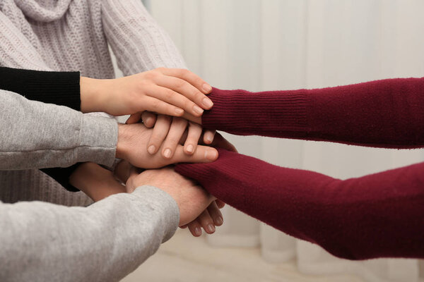 Young people putting their hands together on blurred background, closeup