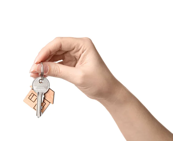 Жінка тримає ключ будинку з дрібничкою на білому тлі, крупним планом — стокове фото